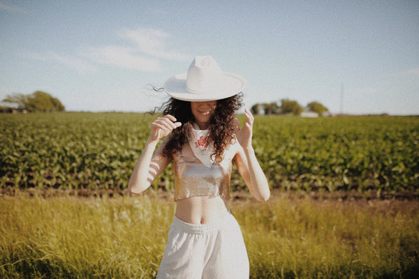 woman wearing cowboy hat and bandana in a field